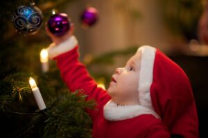 Child holding ornament on a Christmas tree